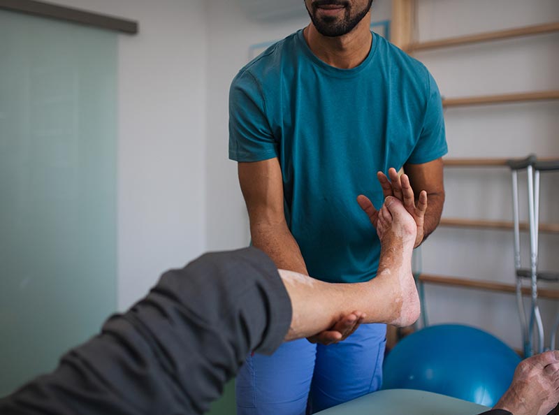 fizjoterapełta rozciągający nogę pacjenta